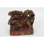 Oriental stone lion with red and gilt painted decoration on rectangular base