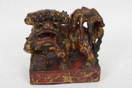 Oriental stone lion with red and gilt painted decoration on rectangular base