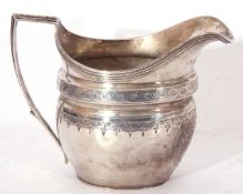 George III helmet cream jug of waisted oval form, bright cut and punched decoration, reeded rim