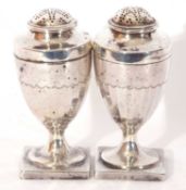 Pair of George III silver peppers of urn form, pull off pierced lids and panelled bodies to a square