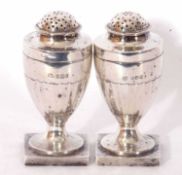 Pair of late Victorian peppers of urn form with pierced pull off lids, panelled bodies to a square