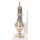 George V silver caster of baluster form, pull off pierced lid with urn finial on a spreading