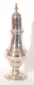 George V silver caster of baluster form, pull off pierced lid with urn finial on a spreading