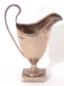 Georgian helmet style cream jug of typical form with a rivet style border and reeded scroll handle