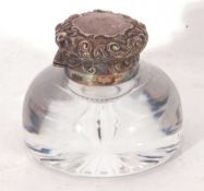 Circular clear glass inkwell with star cut base, hinged silver lid with embossed floral and