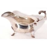 Edward VII silver sauce boat of typical form, card cut rim with flying scroll cap leaf handle on