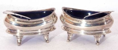 Pair of George III boat shaped salts, each supported on four curved feet, with blue glass liners and