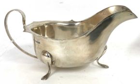 George V silver sauce boat of typical form, having a card cut rim, scroll handle and supported on