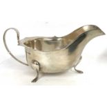 George V silver sauce boat of typical form, having a card cut rim, scroll handle and supported on