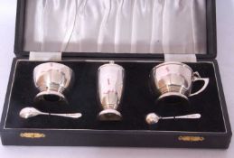 Cased three piece silver condiment set comprising a hinged mustard and spoon, open salt, both with