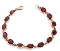Modern 9ct gold and garnet set line bracelet featuring 13 oval faceted garnets in cut down settings,