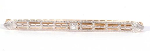 Art Deco diamond set bar brooch, the ornate pierced bar centring a small brilliant cut diamond,