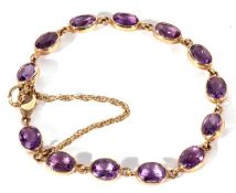 Modern 9ct gold and amethyst line bracelet featuring 13 oval faceted amethysts in cut down settings,