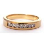 Seven stone diamond ring, channel set with seven small round brilliant cut diamonds, stamped 750,