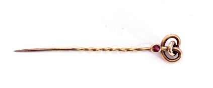 9ct stamped stick pin of a knotted design with a small bezel set ruby highlight