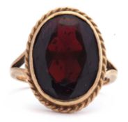 9ct gold garnet ring, the large oval faceted garnet 15 x 10mm, bezel set and raised in a rope