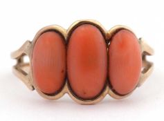 Vintage coral three stone ring featuring three graduated oval stones between pierced shoulders and