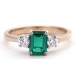 Emerald and diamond three stone ring, the step cut emerald flanked by two round brilliant cut