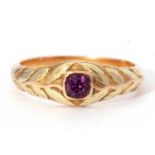 Mid-grade yellow metal ring centring a small round faceted amethyst between foliate chased