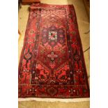 20TH CENTURY MIDDLE EASTERN WOOL FLOOR RUG DECORATED WITH A STYLISED FLORAL DESIGN ON A RED