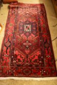 20TH CENTURY MIDDLE EASTERN WOOL FLOOR RUG DECORATED WITH A STYLISED FLORAL DESIGN ON A RED