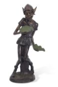 A contemporary bronzed metal model of a pixie holding two leaves, set on a circular base, 77cm high