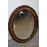 LATE 19TH CENTURY OVAL BEVELLED WALL MIRROR IN DARK WOOD FRAME WITH CARVED DECORATION, 87CM HIGH