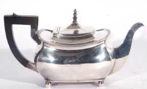 A George V silver teapot of squat rectangular form, having applied urn finial to a hinged lid