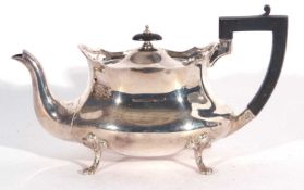 George V shaped oval tea pot with wavy apron, ebonised handle, raised on four trefoil and paw