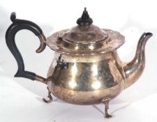 George V teapot of circular baluster form with shaped rim, ebonised handle and finial, supported