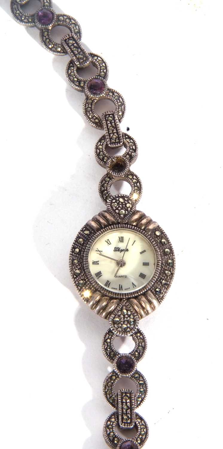 White metal ladies wrist watch featuring a mother of pearl dial with various coloured stones on