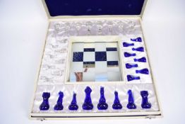 An unusual glass chess set and board in white wooden case