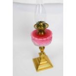 19th century brass oil lamp with pink glass shade, moulded in relief, above brass mounts