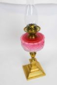 19th century brass oil lamp with pink glass shade, moulded in relief, above brass mounts