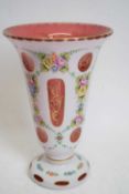 Bohemian type glass vase, cranberry coloured, with white overlay, painted with flowers, 23cm high