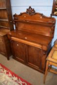 Victorian mahogany chiffonier of typical form with single shelf back, carved pediment and a base