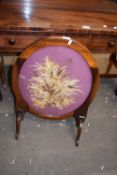 Early 20th century mahogany framed oval screen set with dried flowers and raised on four legs,