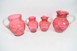 Group of four Victorian cranberry water jugs, two with glass tree-like handles (4)