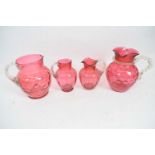 Group of four Victorian cranberry water jugs, two with glass tree-like handles (4)