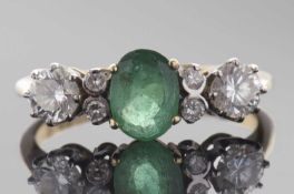 Emerald and diamond ring centring an oval cut emerald, flanked by four small diamonds and two