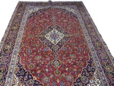Iranian wool floor rug decorated with a large central red and blue panel with stylised floral detail