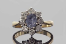 18ct gold sapphire and diamond cluster ring, the pale oval faceted sapphire raised above a small