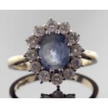 18ct gold sapphire and diamond cluster ring, the oval faceted pale sapphire set within a small
