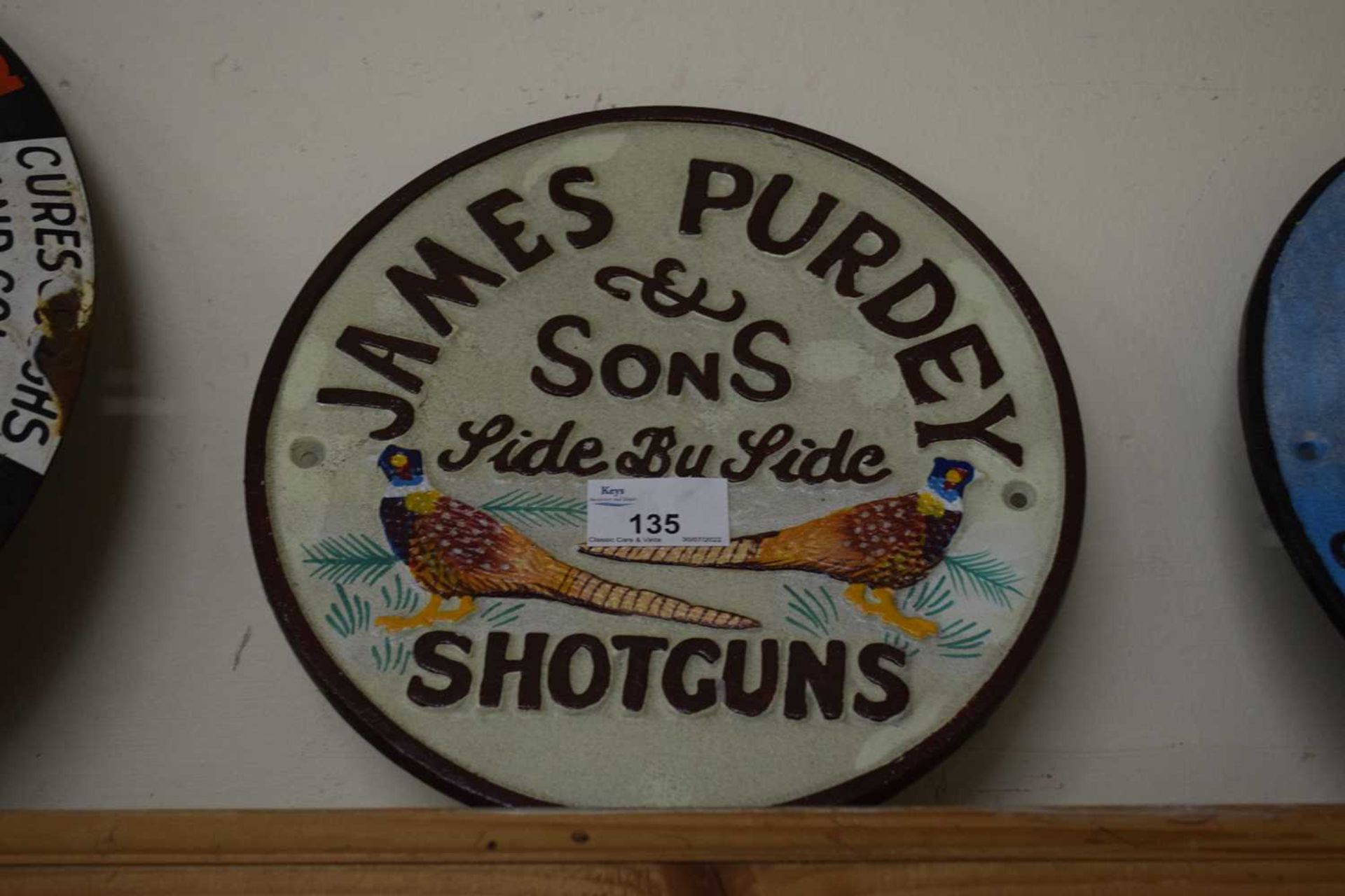 Circular cast iron wall plaque 'James Purdey shotguns'