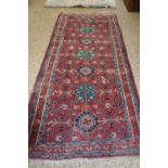 MIDDLE EASTERN WOOL RUNNER CARPET DECORATED WITH GEOMETRIC DETAIL ON A PRINCIPALLY RED BACKGROUND,