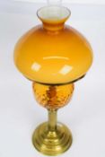 Victorian oil lamp with amber coloured reservoir and amber shade