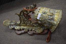 Ornate brass wall mounted bell with pierced floral decorated bracket and oak back board, bell 19cm
