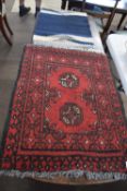 Small Bokhara type wool prayer mat decorated with two lozenges on a red background, together with