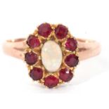 Opal and garnet cluster ring centring an oval cabochon opal raised within a small garnet surround (