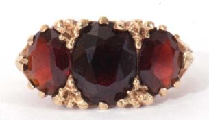 9ct gold three stone garnet ring featuring three graduated oval garnets, each claw set in a carved